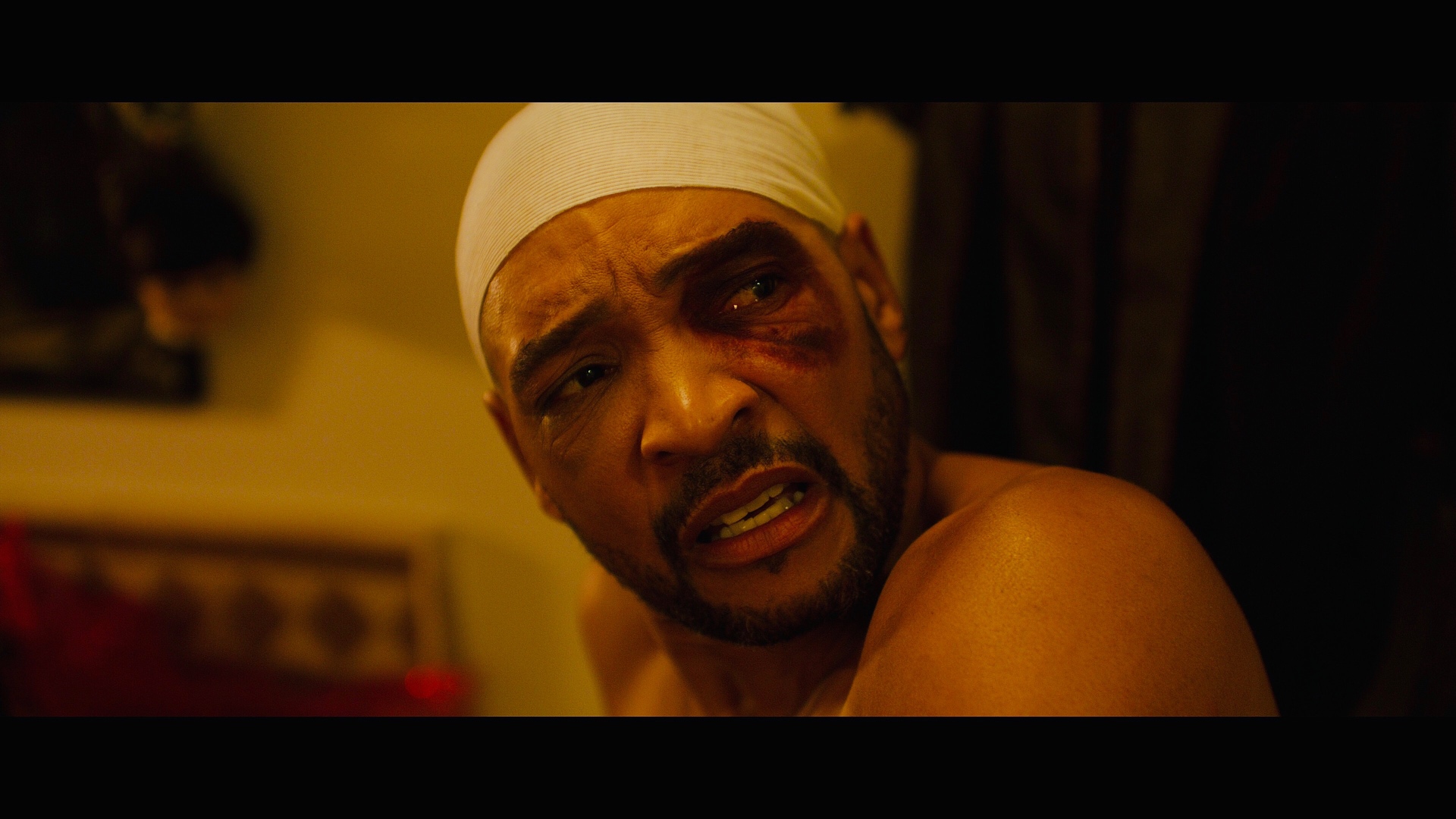 Dogbelly film still: bandaged character lit by warm amber tones.