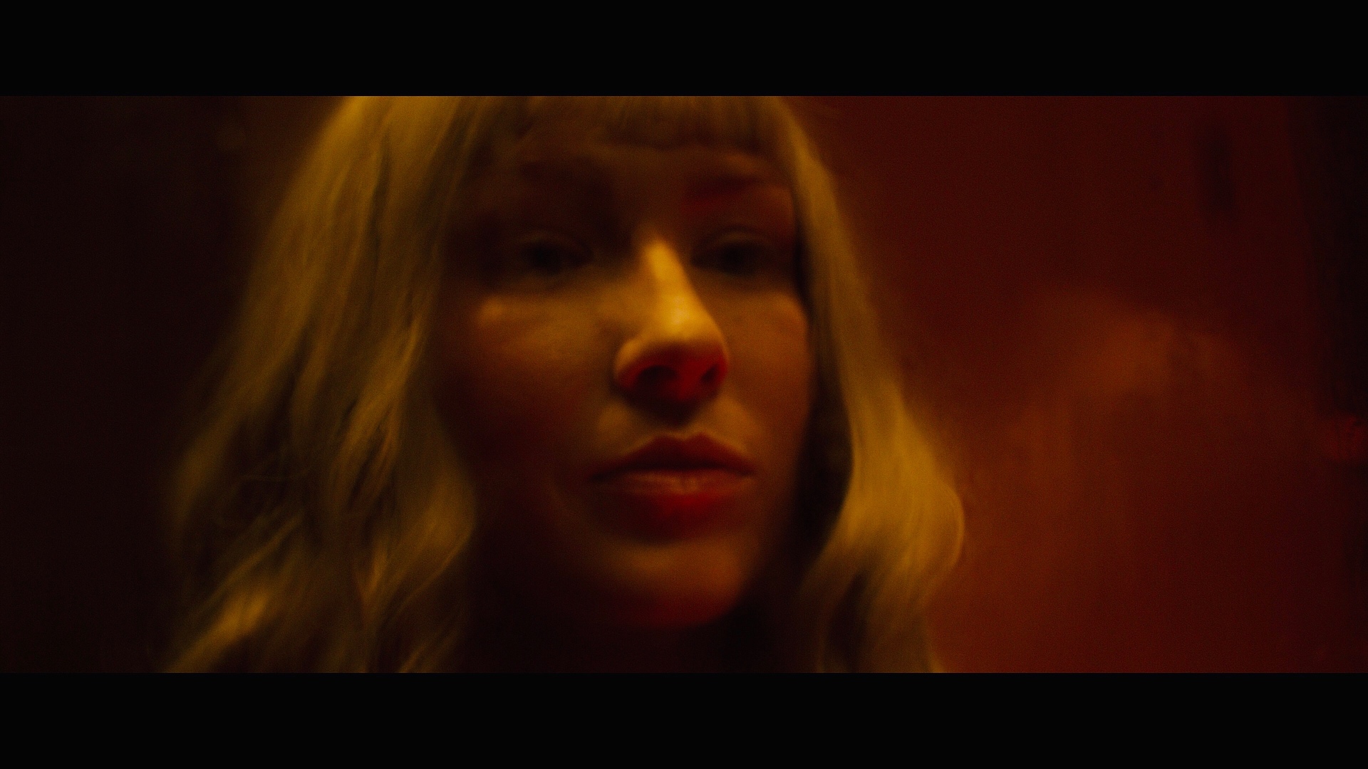 Dogbelly film still: blonde character in moody red light.